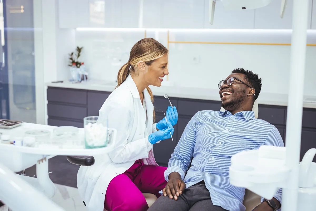 African American young man having a visit at the dentist's. He is sitting on chair at dentist office in dental clinic.. Happy dentist and patient in dentist's office. My dentist is the best!